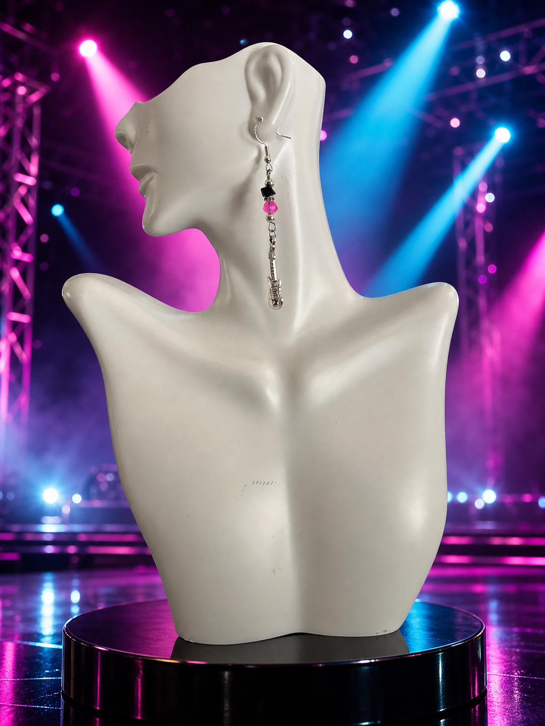 Pink microphone and guitar dangle earrings presented against a vivid 1980s-inspired concert stage