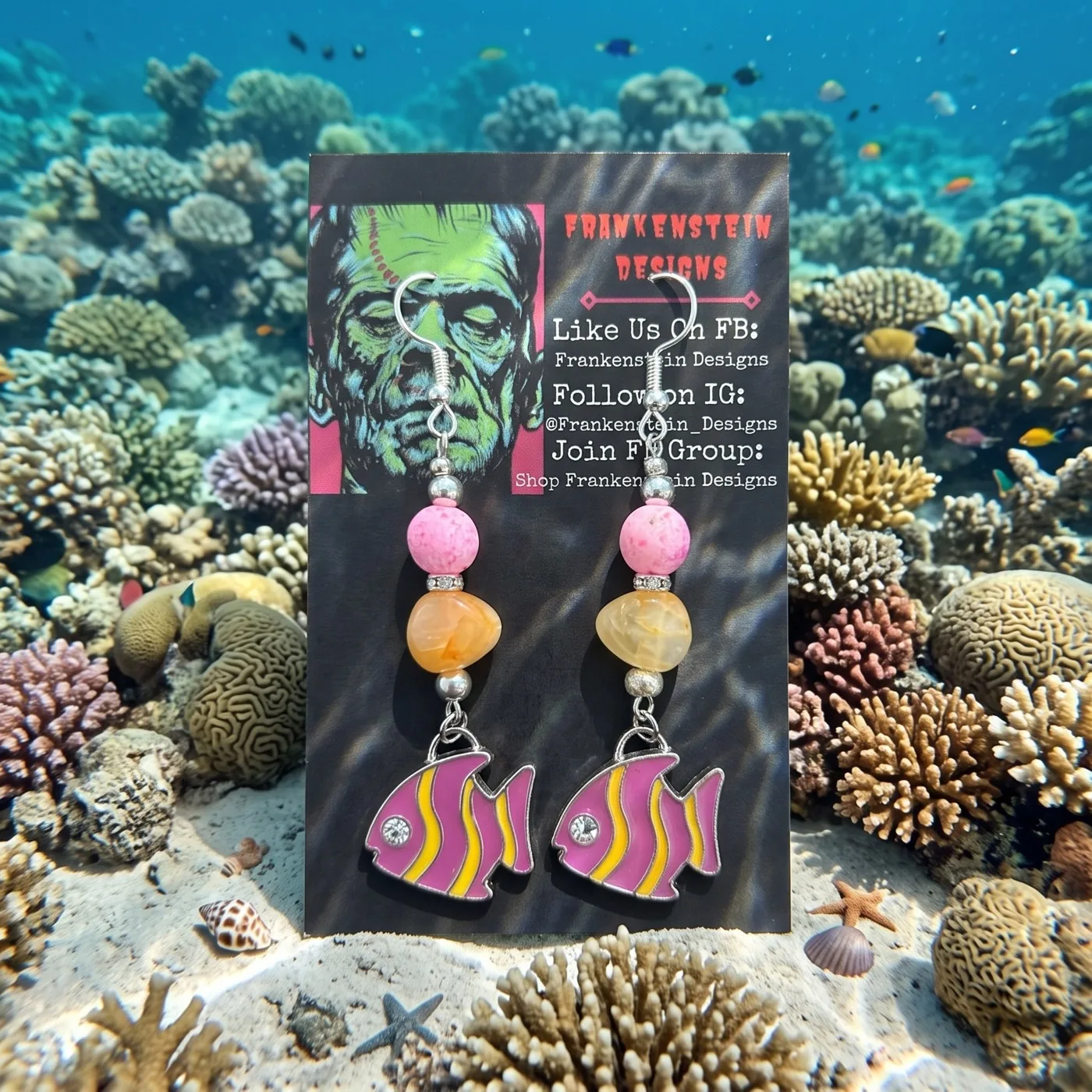 Pink tropical fish earrings displayed against a coral reef