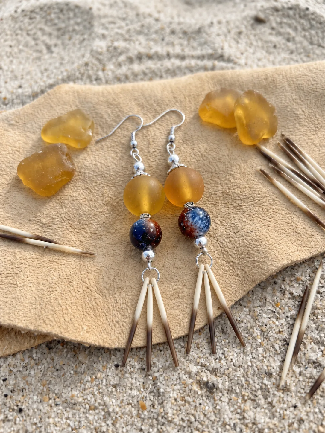Yellow sea glass earrings with three porcupine quills on each earring, arranged on a natural flat-lay